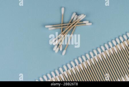 Flache Laienzusammensetzung mit Wattestäbchen auf blauem Grund. Natürliche Baumwollstäbchen aus Baumwolle und Rohrstock. Stockfoto