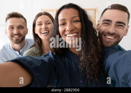 Lächelnde Kollegen nehmen selfie zusammen ins Amt Stockfoto