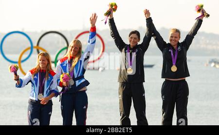 Silbermedaillengewinner, Großbritanniens Hannah Mills (links) und Saskia Clark sowie die Goldmedaillengewinner Jo Aleh und Olivia Powrie (rechts) aus Neuseeland während der Medaillenverleihung am olympischen Segelflugplatz in Weymouth und Portland. Stockfoto