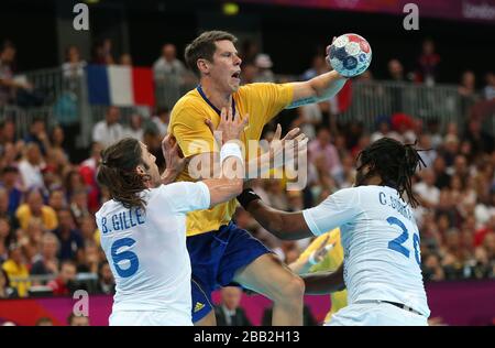 Der schwedische Kim Andersson wird vom französischen Bertrand Gille und Cedric Sorhaindo während des Goldmedaillenspiels des Handball-Wettbewerbs der Männer in der Copper Box Handball Arena, London, in Angriff genommen. Stockfoto