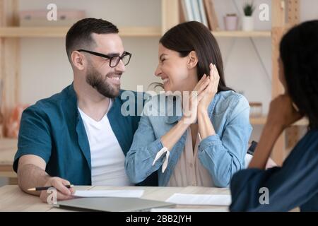 Aufgeregte junge Paare unterzeichnen Deal bei Bürotreffen Stockfoto