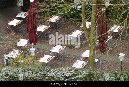 Hamburg, Deutschland. März 2020. Eine dünne Schneedecke liegt morgens auf Stühlen und Tischen im Biergarten eines geschlossenen Restaurants. Credit: Marcus Brandt / dpa / Alamy Live News