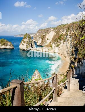 Treppe, die zu einem beliebten Fotopunkt und einem Touristenziel am Atuh Beach auf der Insel Nusa Penida, Bali, Indonesien, mit Felsklippe und tropischem Strand führt Stockfoto