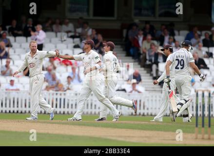 Surreys Zander de Bruyn Center) feiert mit seinem Kapitän Gareth Batty (ganz links), nachdem er den Ball gefangen hat, um das Wicket von Dawid Malan (ganz rechts) von Middlesex für 61 zu nehmen Stockfoto