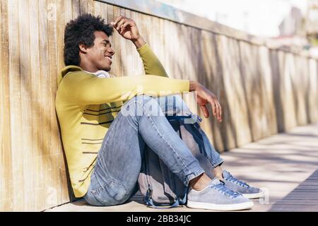 Schwarzer Mann mit Afro Hair und Kopfhörer auf dem Boden. Stockfoto