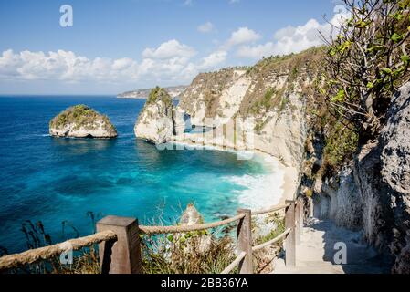 Treppe, die zu einem beliebten Fotopunkt und einem Touristenziel am Atuh Beach auf der Insel Nusa Penida, Bali, Indonesien, mit Felsklippe und tropischem Strand führt Stockfoto