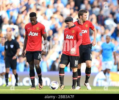 Danny Welbeck (links), Wayne Rooney (Mitte) und Michael Carrick (rechts) von Manchester United sind niedergeschlagen und warten auf einen Neustart des Spiels, nachdem Yaya Toure (nicht im Bild) von Manchester City das zweite Tor seines Teams erzielt hat Stockfoto