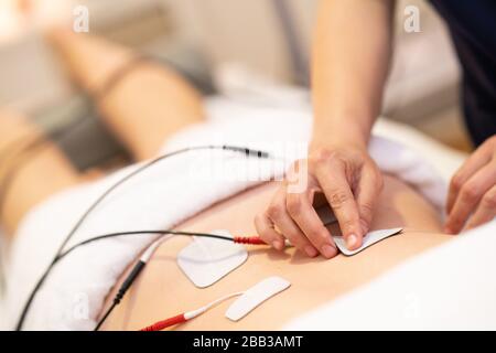 Elektrostimulation in der physikalischen Therapie mit einer jungen Frau Stockfoto