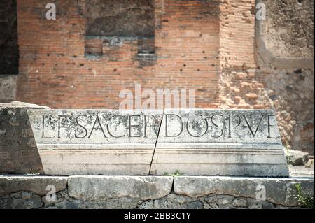 Lateinische Aufschrift, die einst Teil des Marmorportikus war, der um die Spitze der Kolonnade des Forums in Pompeji, Italien, verlief Stockfoto