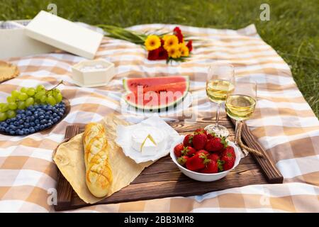 Romantisches Picknick in der Natur. Die Schönheit der untergehenden Sonne, frisches Obst und Wein. Stockfoto