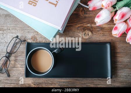 Kaffee in schwarzer Tasse mit Tablett und schöner Mockup-Dekoration auf Holztisch. Vogelperspektive, Mock-up-Konzept Stockfoto