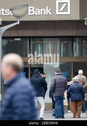 Duisburg, Deutschland. März 2020. Kunden einer Bank stehen in einer Warteschlange vor dem Eingang. In Nordrhein-Westfalen gibt es ein Versammlungsverbot für mehr als zwei Personen unter Ausschluss von Familien, um die weitere Ausbreitung der Coronavirus-Pandemie zu verlangsamen. Kredit: Roland Weihrauch / dpa / Alamy Live News Stockfoto