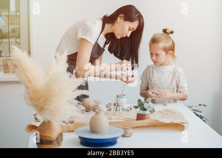 Sie zeigt die korrekte Arbeit von Tonwaren, Meister und Lehrling im Keramikstudio Stockfoto