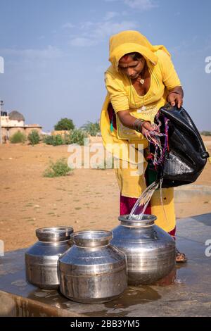 Frau, die Wasser aus einem Brunnen der Gemeinde, Thar-Wüste, Rajasthan, Indien, sammelt Stockfoto