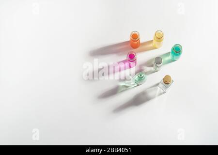 Parfüm in einer transparenten Flasche, aromatische Öle. Farbiger Schatten auf weißem Hintergrund. . Aromatherapie, Parfümherstellung.Raum für Text. Stockfoto