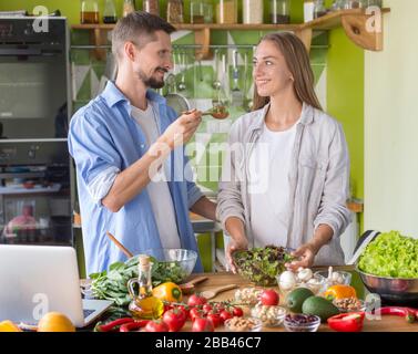 Mann, der seiner Frau gibt, leckeren frischen Salat mit Kürbis zu probieren Stockfoto