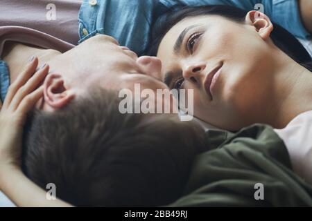 Nahaufnahme des liebevollen Paares, das sich zärtlich umarmt, während er zusammen liegt, kopiere Raum Stockfoto