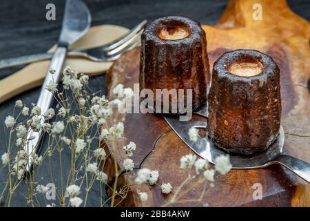 Cannelés (Canelés) de Bordeaux Rezept ist ein kleines Gebäck mit Rum und Vanille auf einer Holzplatte. Traditionelles französisches Süßspeisen. Leckere Snacks. Obristin Stockfoto