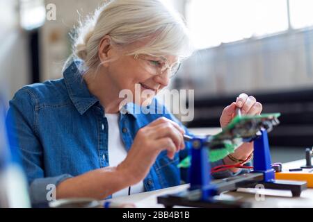 Seniorin in der Elektronikwerkstatt Stockfoto