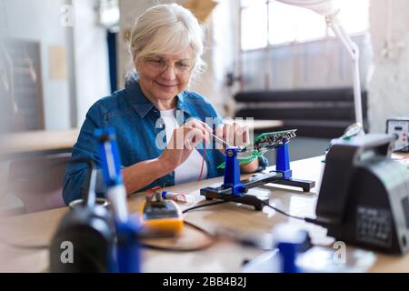 Seniorin in der Elektronikwerkstatt Stockfoto