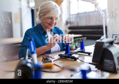 Seniorin in der Elektronikwerkstatt Stockfoto