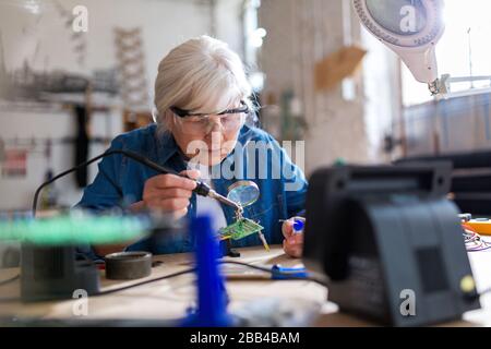 Seniorin in der Elektronikwerkstatt Stockfoto