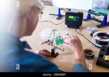 Seniorin in der Elektronikwerkstatt Stockfoto