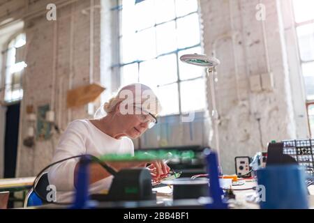 Seniorin in der Elektronikwerkstatt Stockfoto