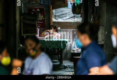 Quezon City. März 2020. Anwohner, die Gesichtsmasken tragen, warten am 30. März 2020 auf Hilfsgüter in einem Slumgebiet in Quezon City, den Philippinen. Credit: Rouelle Umali/Xinhua/Alamy Live News Stockfoto