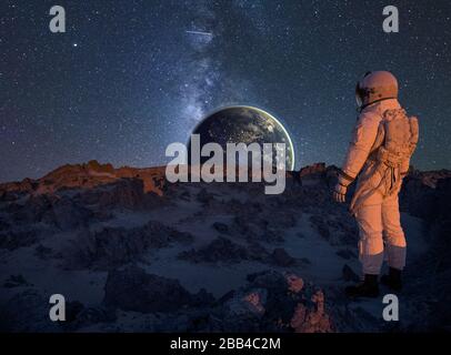 Astronaut betrachtet die Erde von der Oberfläche eines außerirdischen Planeten aus Stockfoto