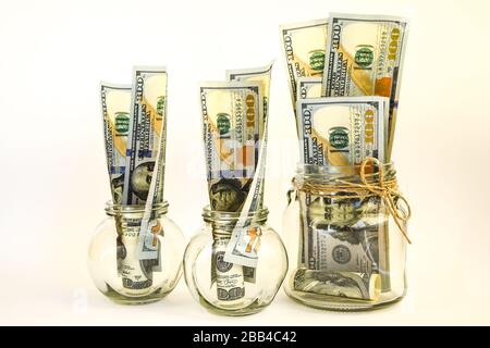 Glasgefäße gefüllt mit Dollarscheinen, Einsparungen im Glasbecher, Geld isoliert auf Weiß Stockfoto