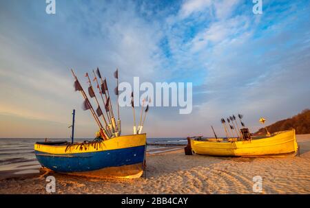 Bunte Fischerboote an einem sandigen Meeresstrand während eines schönen Sonnenuntergangs Stockfoto