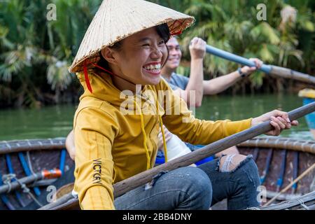 Passagiere, die in Hoi an in einem Korakelboot rudern Stockfoto