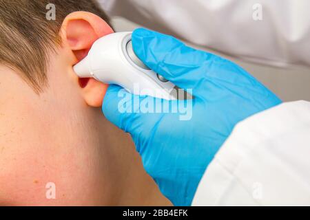 Porträt einer Krankenschwester oder eines Arztes, die die Temperatur eines Kindes mit einem elektronischen Thermometer messen Stockfoto