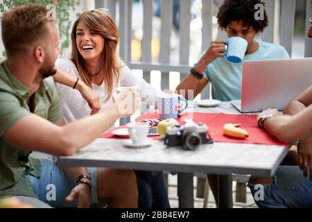 Fröhliche Freunde sitzen zusammen am Tisch outdor Stockfoto