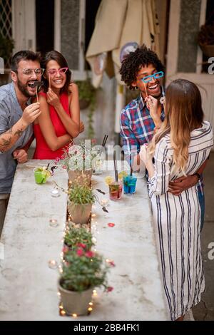 Junge glückliche Freunde im Café haben Spaß mit Requisiten Stockfoto