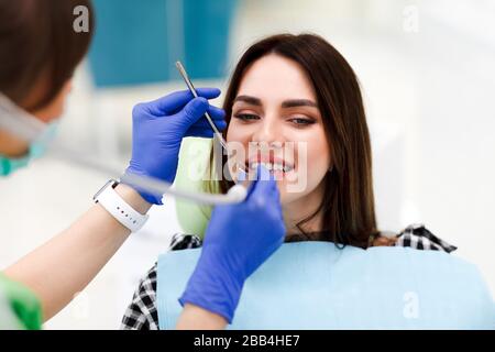 Frau in der Zahnmedizin Zahnarzt behandelt Zähne zu seinem hübschen Patienten. Zahnarzt bohrt die Zähne des Patienten Stockfoto