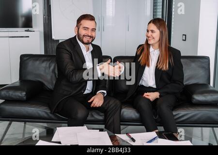 Mann und Frau in ungezwungener Atmosphäre schütteln am Ende des Deals die Hände. Stockfoto