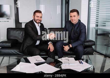 Zwei zufriedene Geschäftsleute schütteln nach erfolgreichen Verhandlungen die Hand, Geschäftspartner im offiziellen tragen Handschlag, machen einen Deal und nehmen einen aus Stockfoto