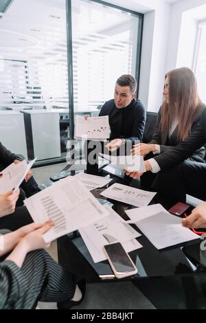 Happy Project Manager erstellt einen Finanzbericht, zeigt wachsende Statistiken und wachsende Zeitpläne für Kollegen, ist zufrieden mit der hohen Geschwindigkeit von d Stockfoto