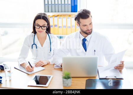 Zwei Personen: Facharzt und Brillenassistent kooperieren durch Analyse und Schreiben der Diagnose Stockfoto