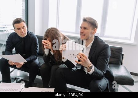 Erfolgreiche junge Architekten am modernen Arbeitsplatz, die ein kreatives Treffen führen. Gruppenleiter, der Diagramme und Diagramme präsentiert, der glückliche Projektmanager führt eine durch Stockfoto