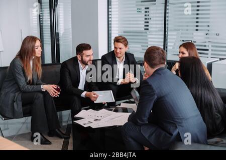 Treffen von Geschäftspartnern in einem modernen Büro, EINER Gruppe erfolgreicher Geschäftsleute. Diskussion eines wichtigen Unternehmensvertrages. Stockfoto