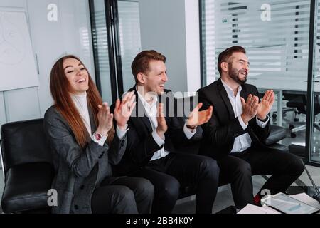 Eine Gruppe von Geschäftsleuten klatscht die Hände, um ihrem Chef zu gratulieren - dem Business Company Team Stockfoto