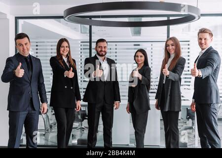 Porträt von fünf Geschäftspartner Daumen halten und mit einem Lächeln in die Kamera schauen Stockfoto