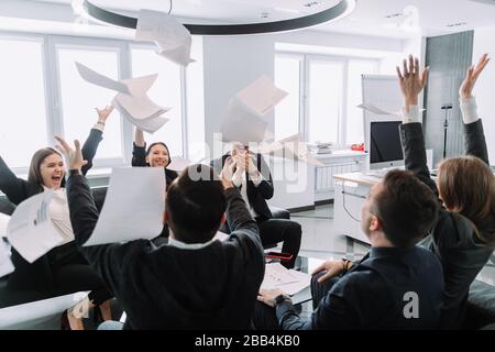 Euphorisch überglücklich feiern diverse Wirtschaftsteams, die Wurfpapiere werfen, den Erfolg des Unternehmenssiegs gemeinsam mit dem Konzept im Büro, das von Wor begeistert ist Stockfoto