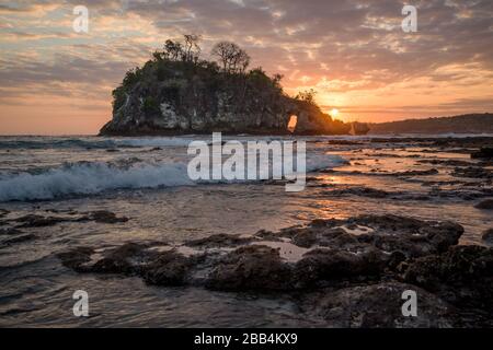 Crystal Bay bei Ebbe mit dem Sonnenuntergang durch die Felsinsel strömende Meerwasser über Felsen und Pfütze in Nusa Penida, Bali, Indonesien Stockfoto