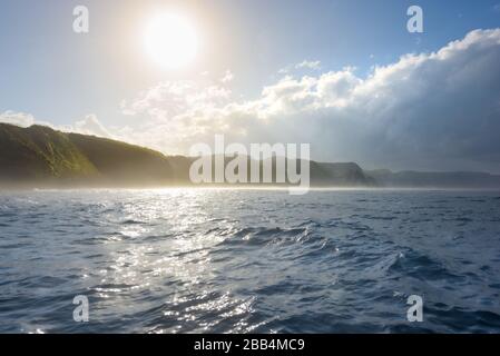 Südküste von Nusa Penida, mit Dschungelklippen und Wasserfällen, die im Meer ragen, bei Sonnenaufgang auf Bali, Indonesien Stockfoto