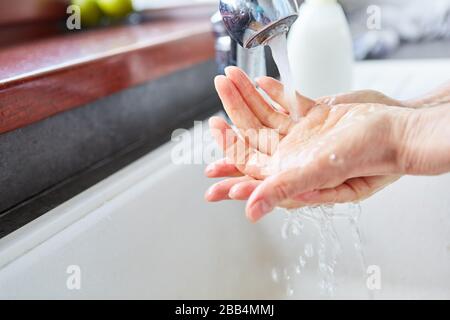 Ältere Frauen waschen ihre Hände mit Seife und Wasser am Waschbecken im Bad, um sich vor dem Corona-Virus zu schützen Stockfoto