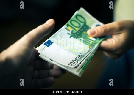 Nahaufnahme der Hand der Person, die Geld an die andere Hand gibt. Übertragung von Euro-Banknoten. Stockfoto